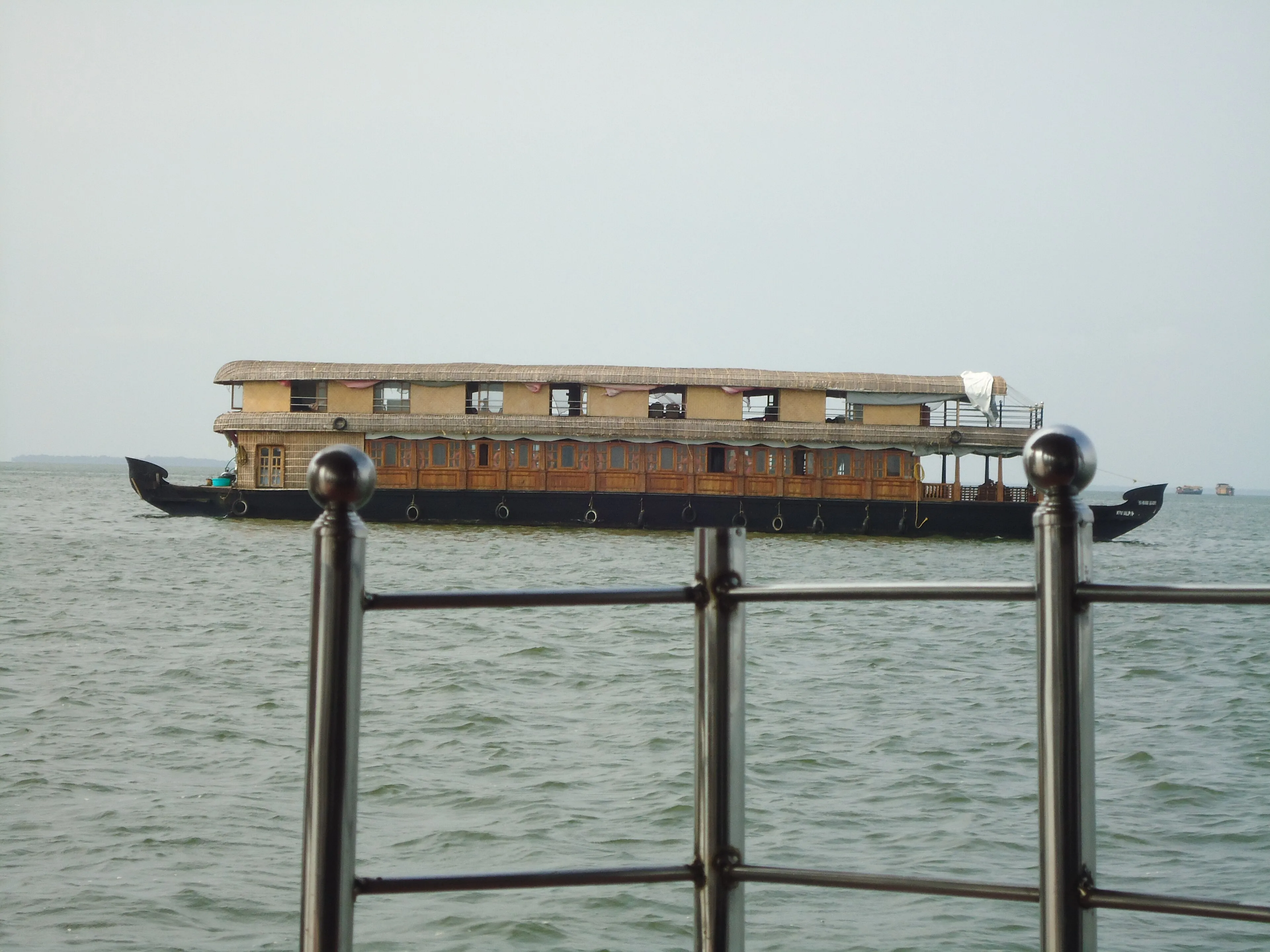 Calm Kerala backwater lined with coconut palms and a distant houseboat