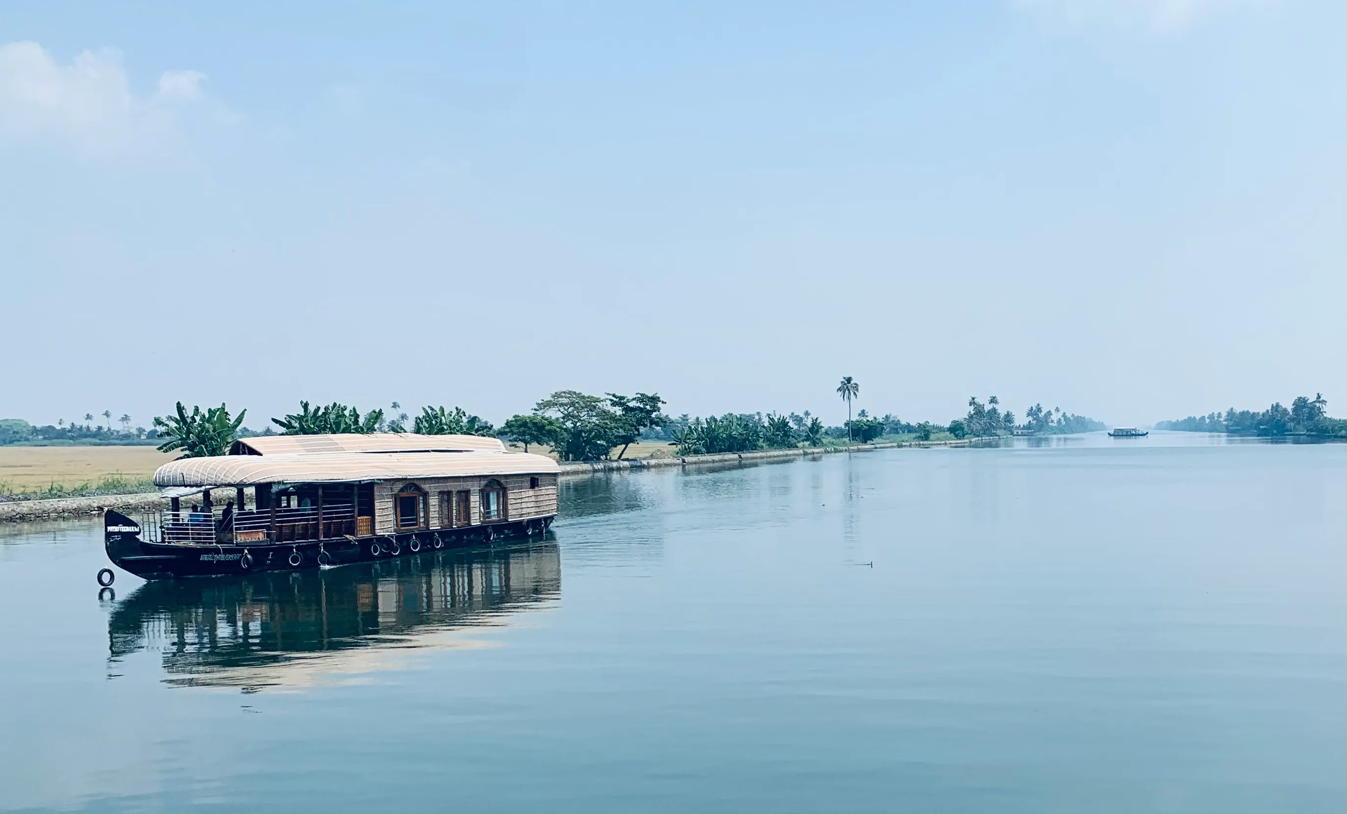 Houseboat gliding through a narrow palm-lined backwater canal in Alleppey