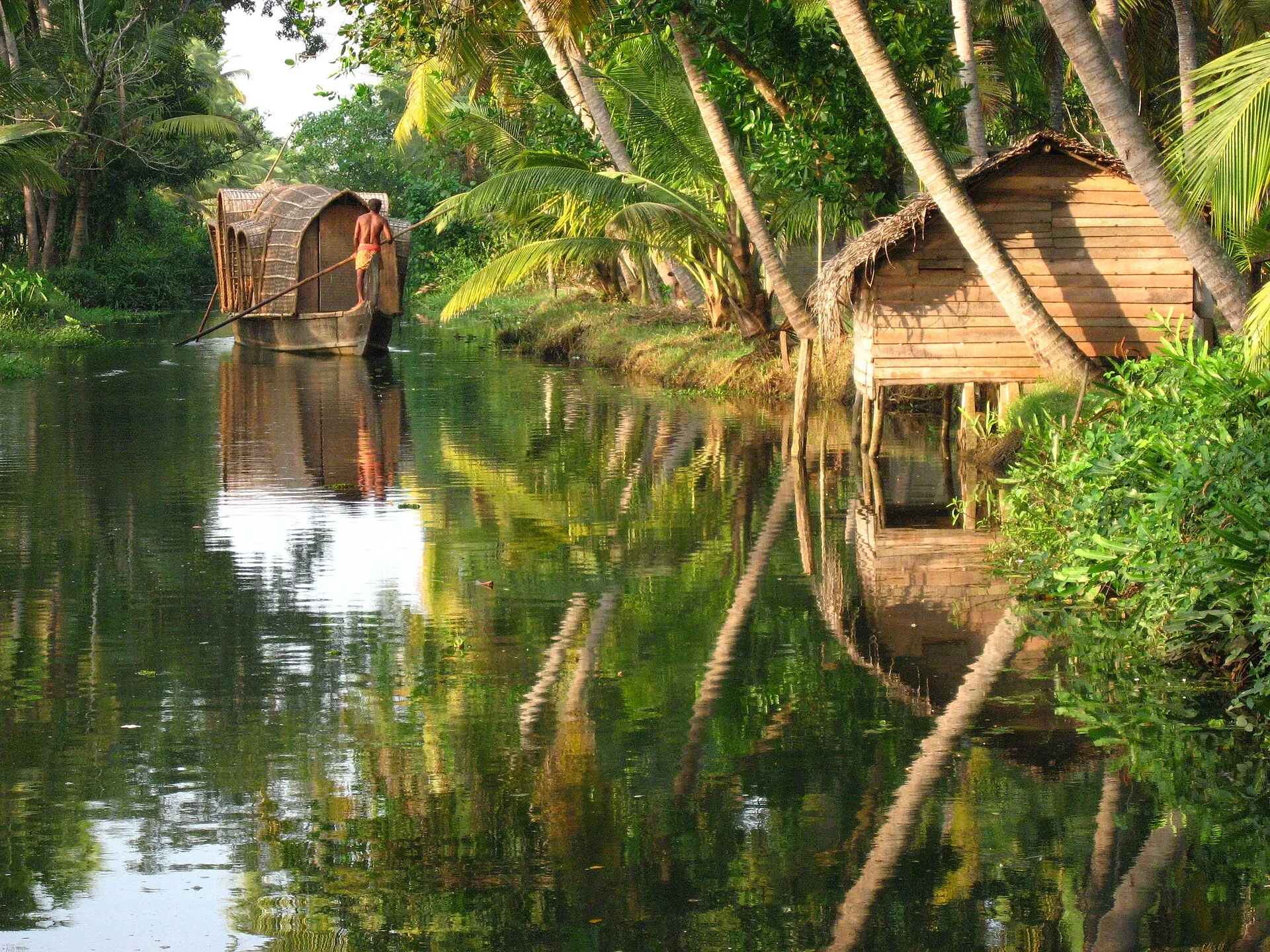 Interior deck of a luxury Alleppey houseboat with teak furnishings overlooking the backwaters